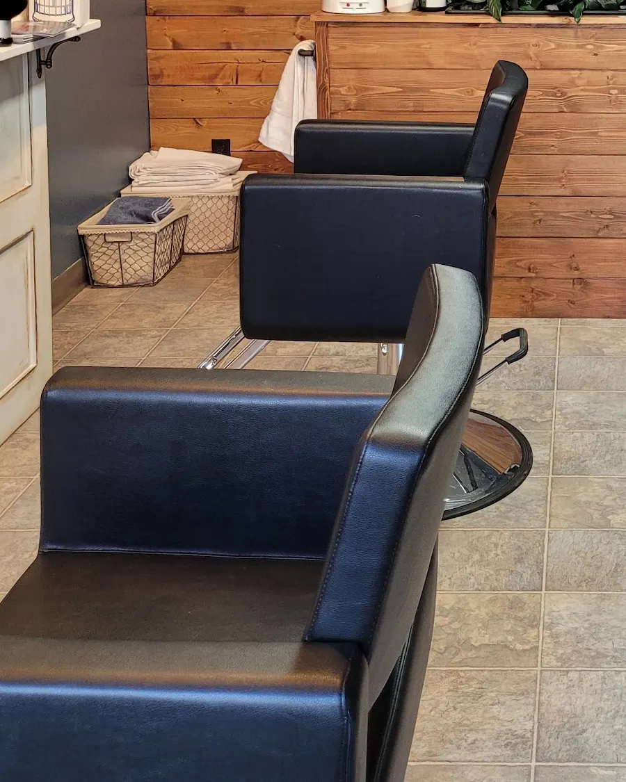 The two black styling chairs waiting on the salon's tiled floor