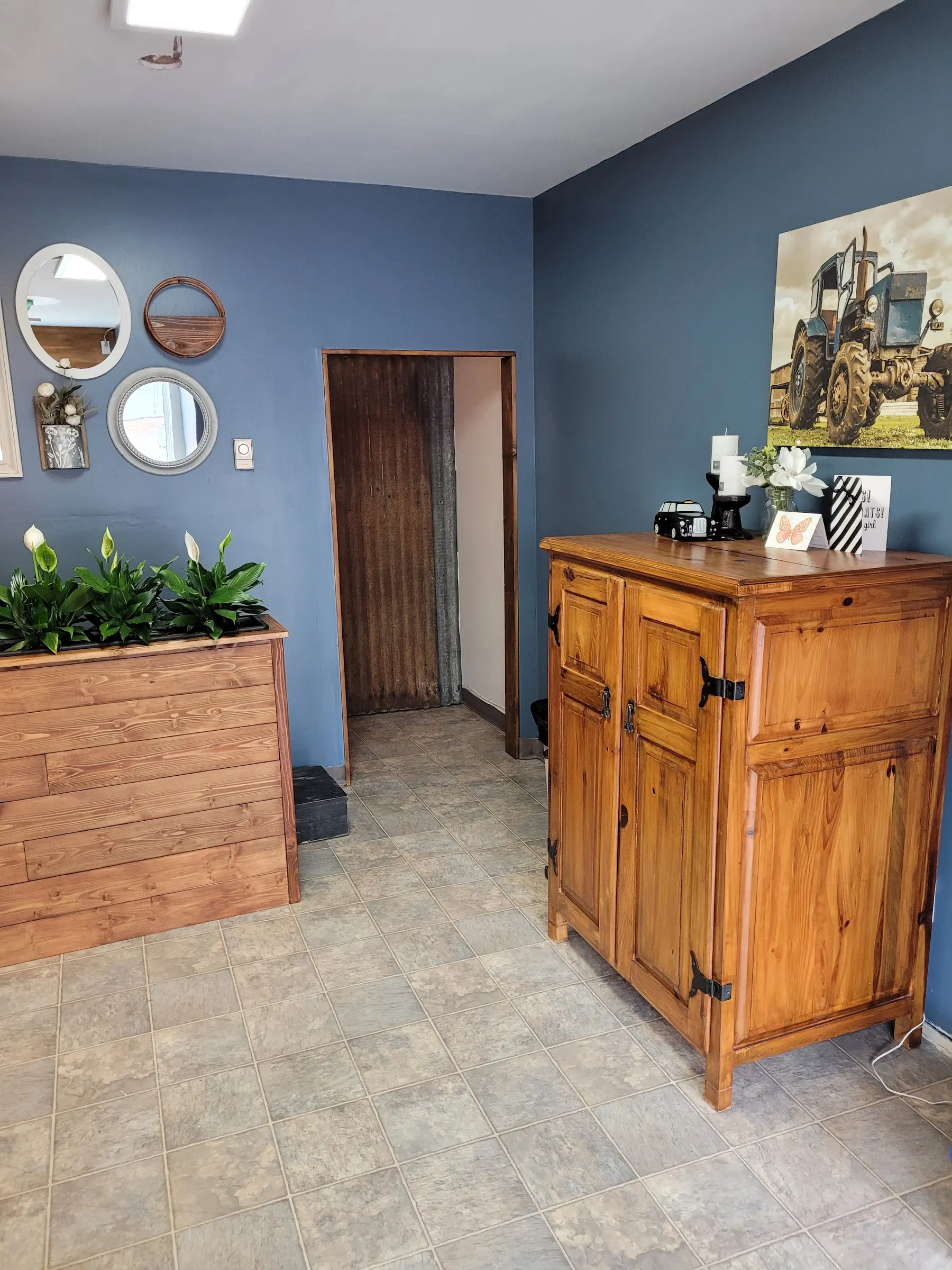 The reception corner of Mane Obsession, with blue walls, a pine cabinet and a cluster of vintage mirrors