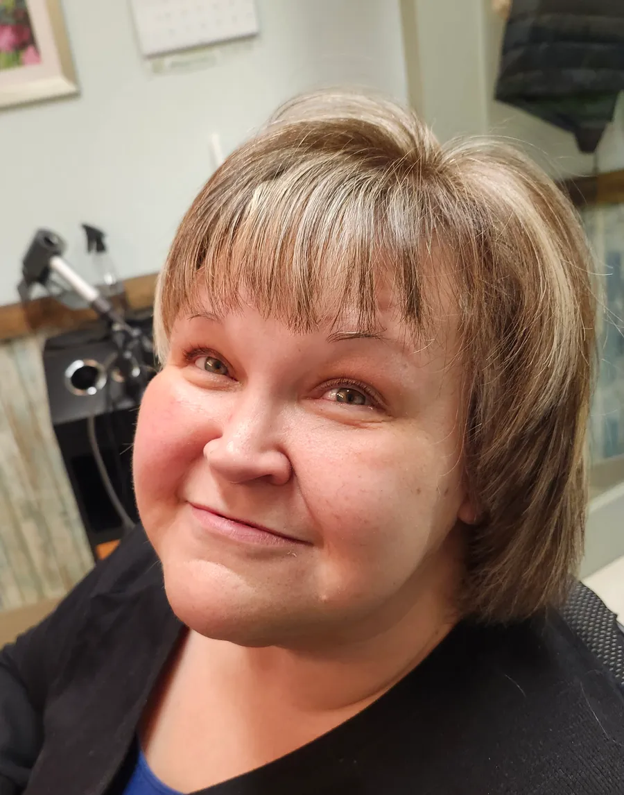 A client smiling in the chair, her short blonde cut blow-dried into shape with a soft feathered fringe