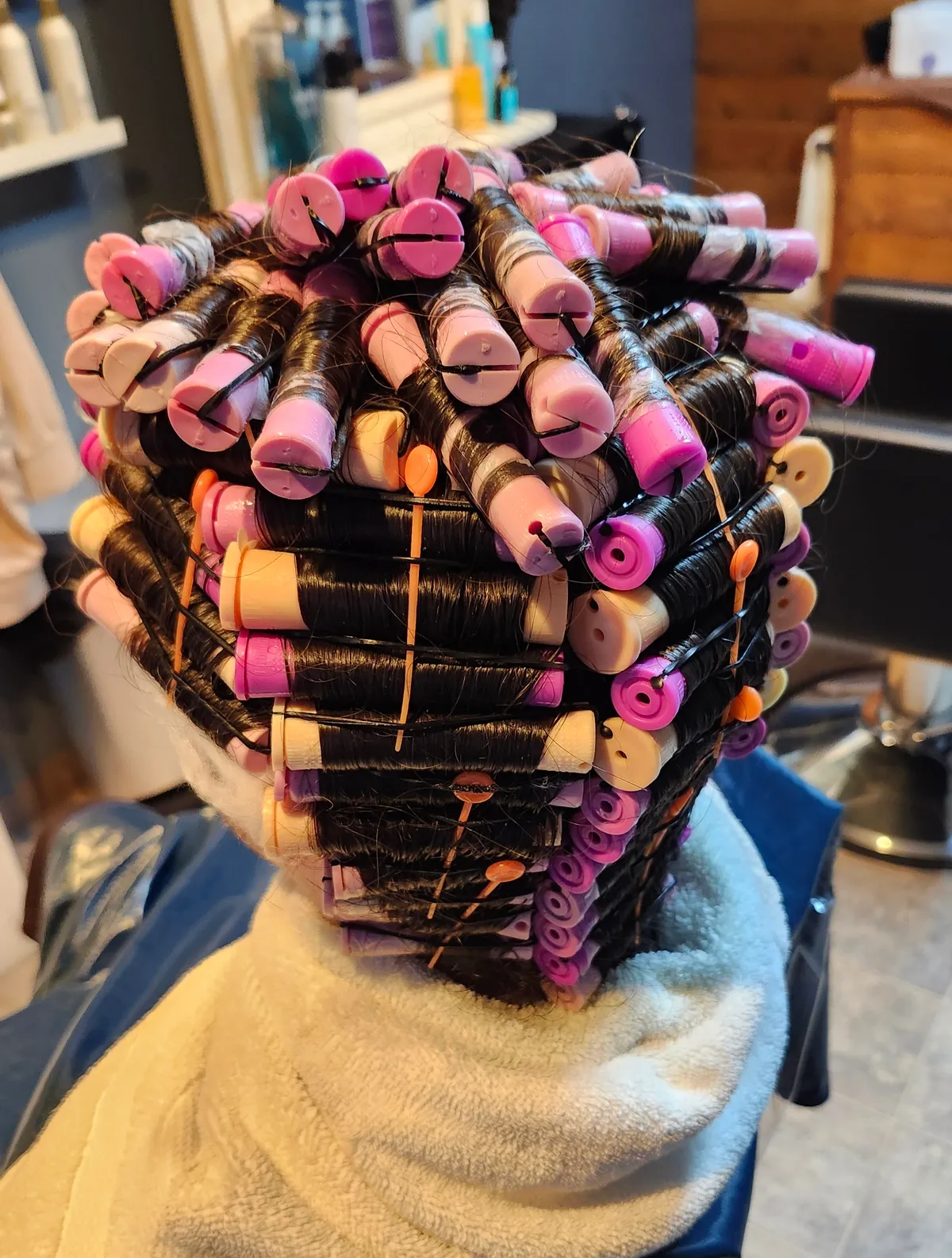 A full head of perm rods wound in, pinks and purples, ready to process